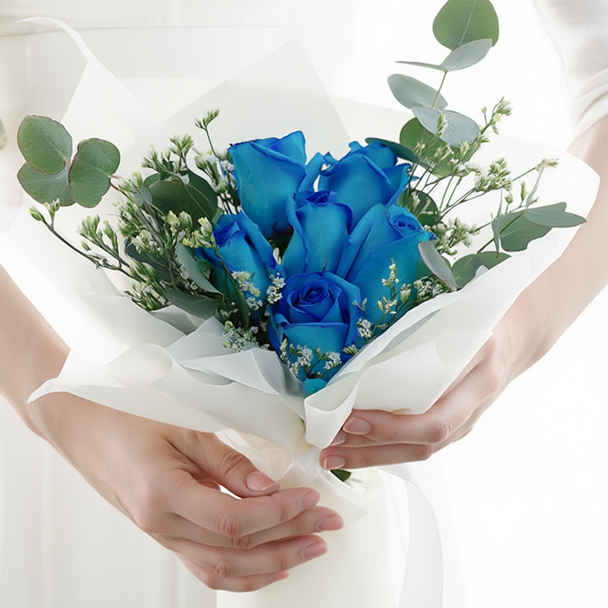 Bouquet of blue roses with greenery held by a person against a white background
