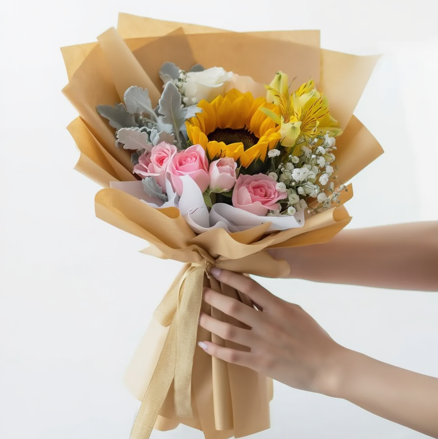 Bouquet of flowers wrapped in brown paper held by a person against a white background