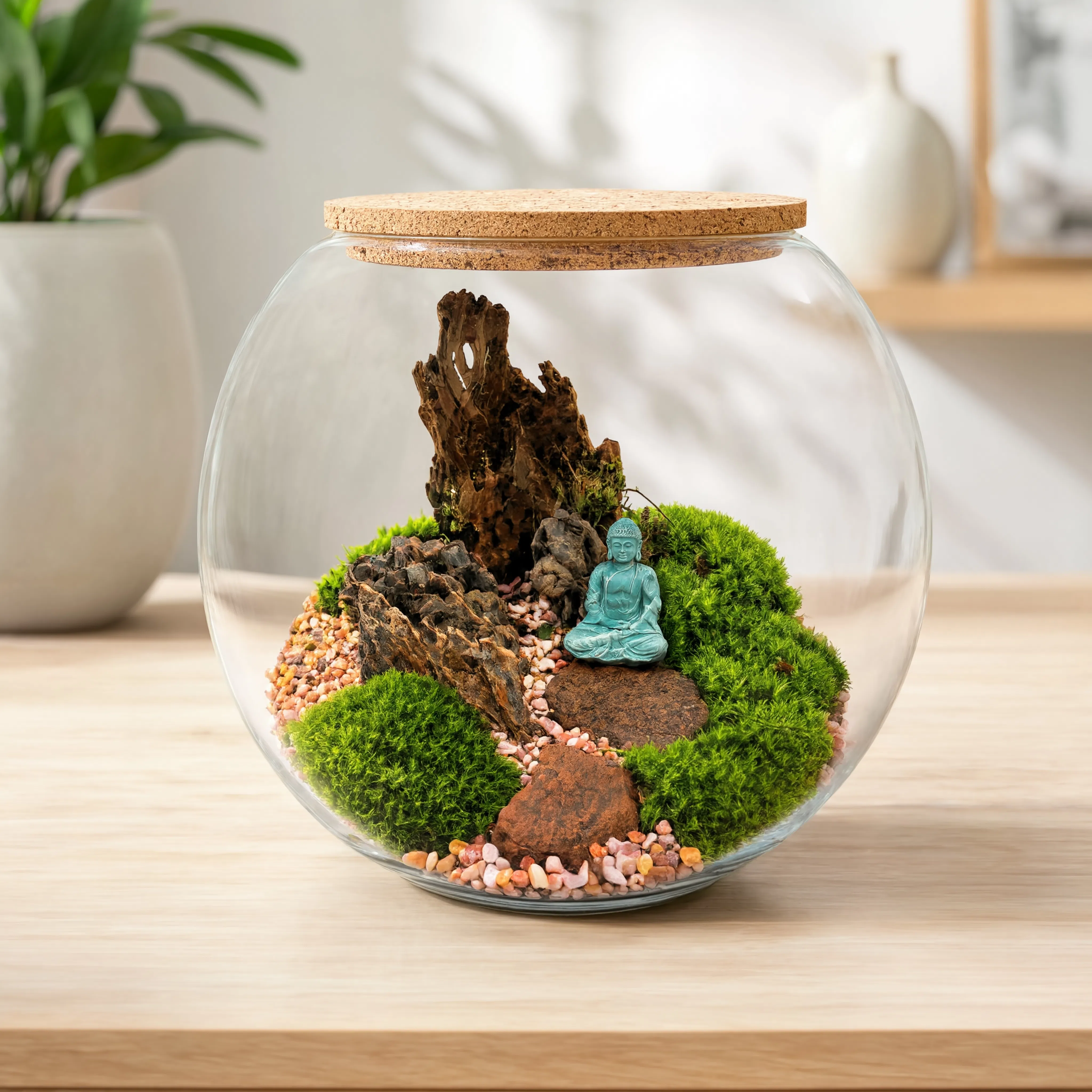 Handcrafted Zen Buddha moss terrarium in a round glass bowl featuring preserved moss, natural driftwood, decorative rocks, pebble pathway, and a Buddha figurine for modern home décor.