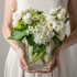 Bouquet of white flowers held by a person wearing a white dress.
