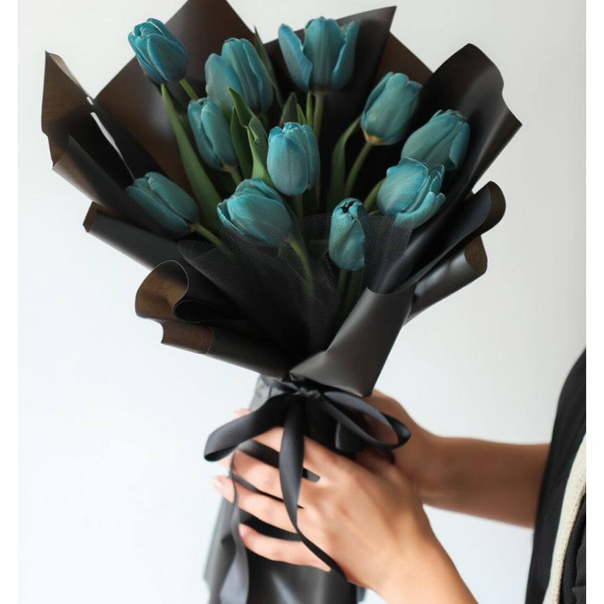 Bouquet of blue tulips wrapped in black paper held by a person against a white background