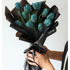 Bouquet of blue tulips wrapped in black paper held by a person against a white background