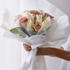 Bouquet of flowers wrapped in white paper held by a person against a white background