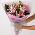 Bouquet of pink flowers wrapped in pink paper with a white background