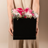 Person holding a black box with pink and white flowers 