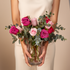 Bouquet of pink and red roses held by a person against a beige background