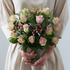 Bouquet of pink and green flowers held by a person wearing a beige dress.