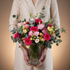 Person holding a bouquet of colorful flowers against a beige background