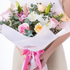 Bouquet of flowers with a pink ribbon held by a person wearing a white shirt.
