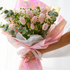 Bouquet of pink tulips wrapped in colorful paper held by a person on a white background