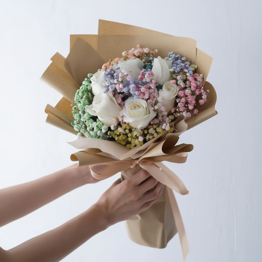 Bouquet of flowers wrapped in brown paper held by a person against a white background