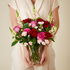 Bouquet of red and pink roses held by a person against a neutral background