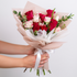 Bouquet of red and white roses held by a person against a light background