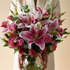 Bouquet of pink and white lilies held by a person against a beige background