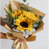 Bouquet of yellow sunflowers wrapped in brown paper with greenery on a light gray background