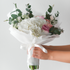 Bouquet of flowers held by a hand against a light gray background