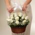 Elegant wooden basket arrangement with 12 white roses, seasonal foliage, and delicate fillers beautifully crafted in a luxury floral design.