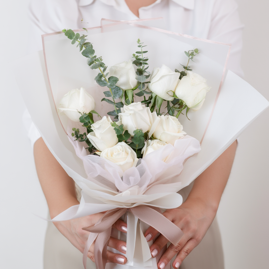 Bouquet of white roses held by a person against a plain background