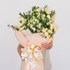 Bouquet of flowers with a decorative bow held by a person against a light background